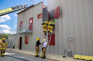 Firefighters climbing ladders during training at a steel fire training building